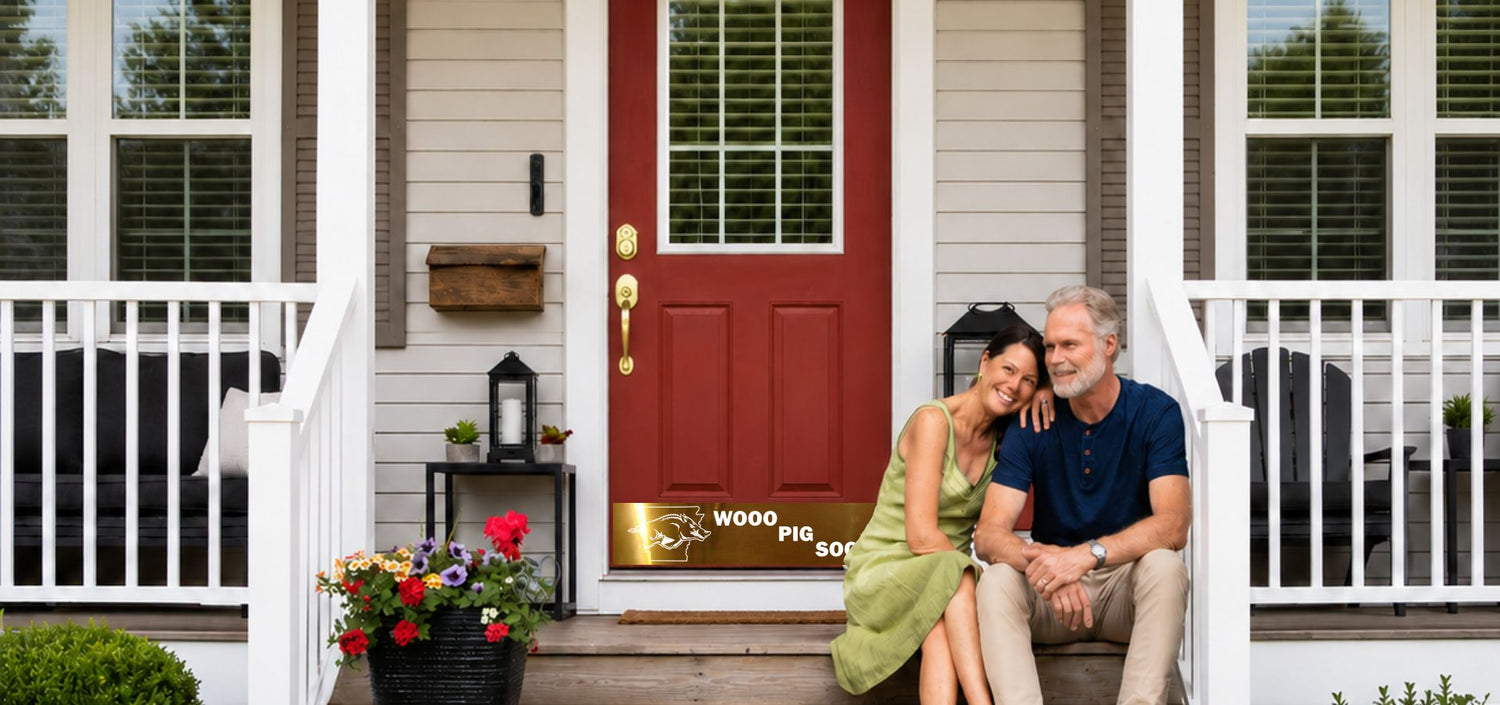 Couple by red front door with Arkansas Razor Backs engraved door kick plate